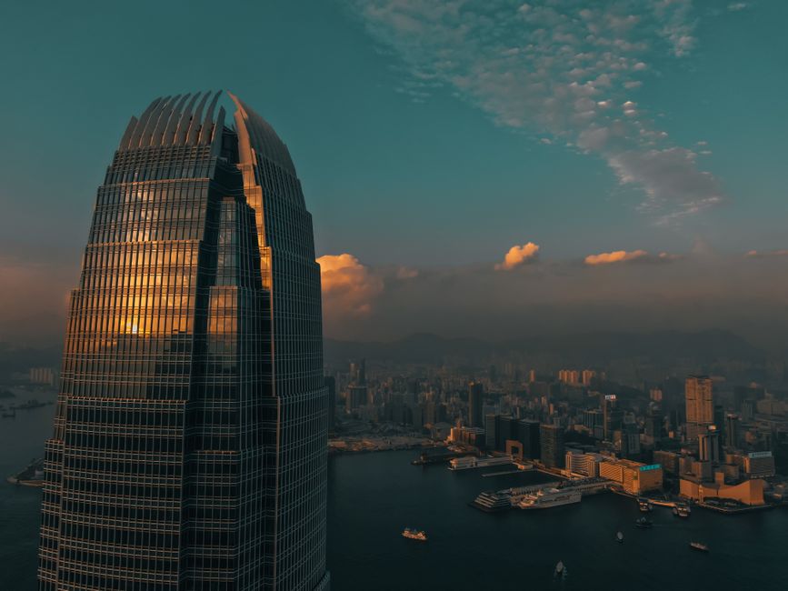 Stunning view of Hong Kong skyline at sunset with a skyscraper reflecting the golden hues.