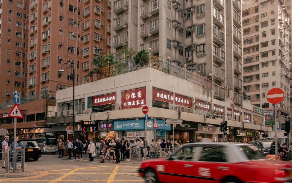 Vibrant Hong Kong street scene with people, high-rise buildings, and a red taxi.